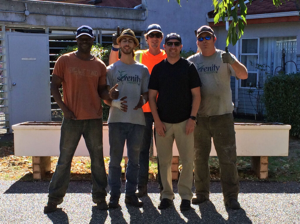 Photo of five Serenity Landscapes employees taken outside on a sunny day.